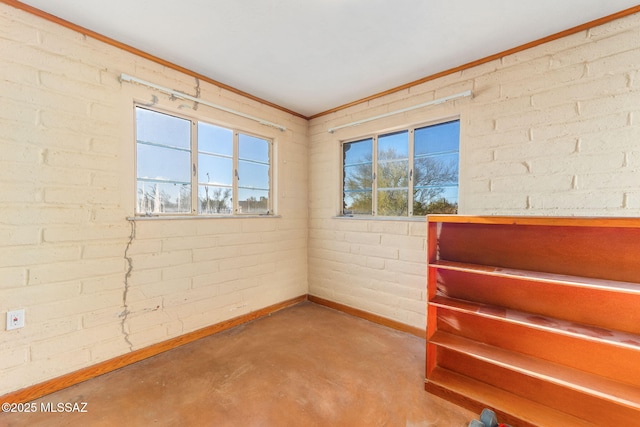 spare room with concrete flooring, brick wall, and baseboards