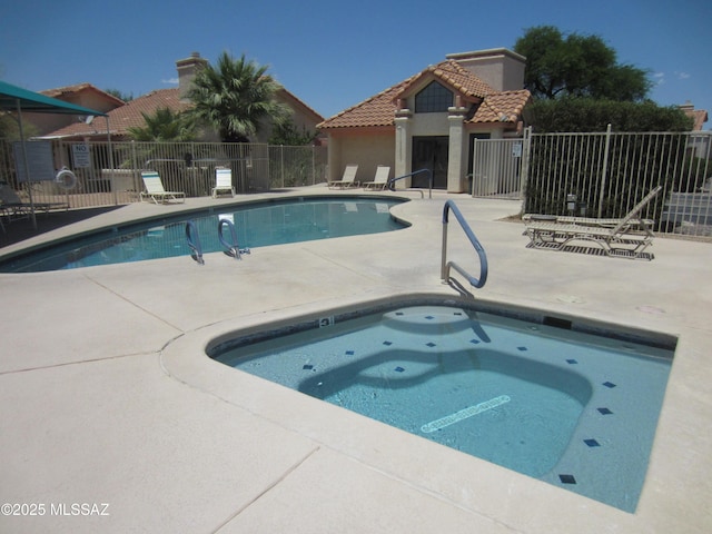 pool with a patio area, fence, and a community hot tub