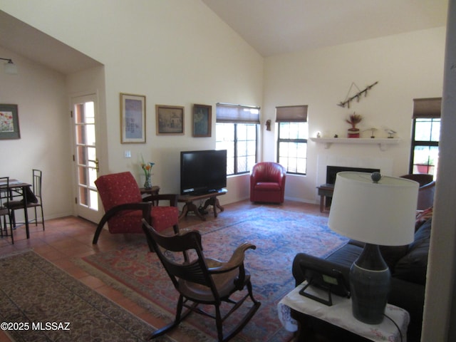 living area with high vaulted ceiling, a fireplace, tile patterned flooring, and baseboards