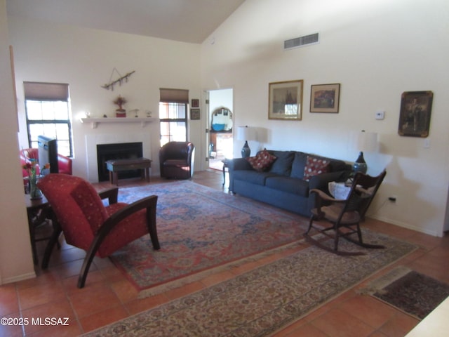 living room featuring high vaulted ceiling, a fireplace, visible vents, and tile patterned floors