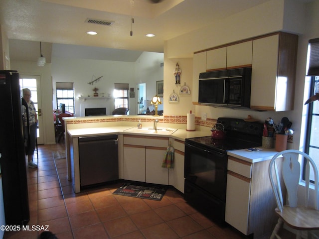 kitchen with a fireplace, light countertops, visible vents, a peninsula, and black appliances