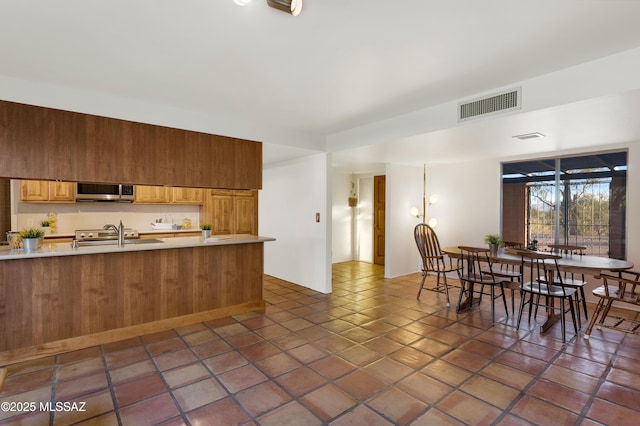 kitchen featuring light countertops, visible vents, stainless steel microwave, and a sink