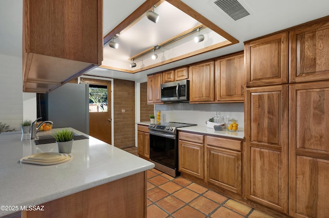 kitchen with stainless steel appliances, light countertops, visible vents, brown cabinetry, and a sink