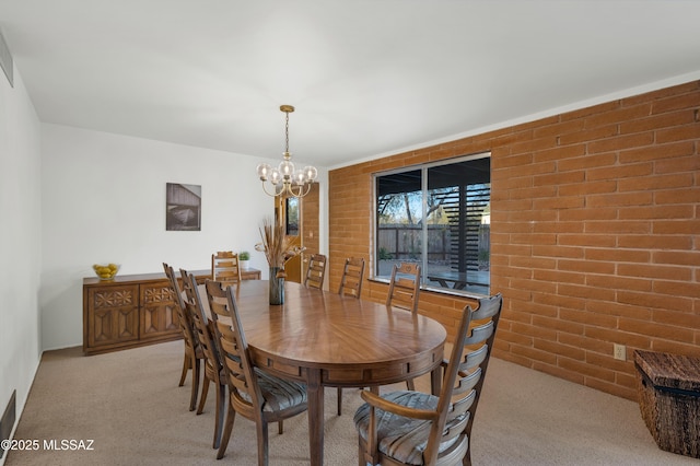 dining room featuring light carpet, a notable chandelier, and brick wall