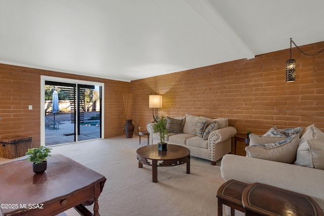 living area with carpet floors, beam ceiling, and brick wall