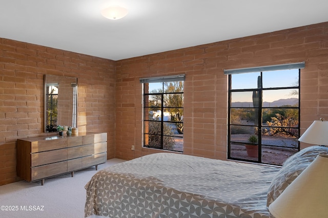 bedroom featuring carpet flooring and brick wall