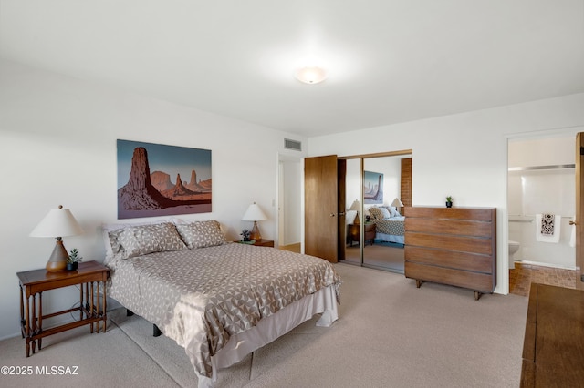 bedroom featuring connected bathroom, visible vents, a closet, and light colored carpet