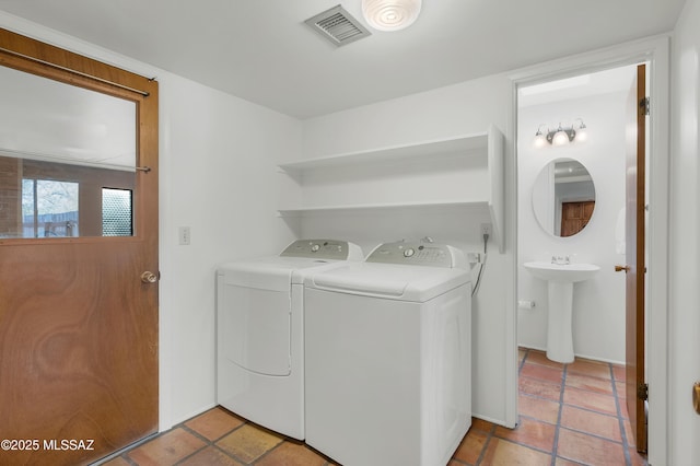 laundry room featuring washing machine and dryer, visible vents, and a sink