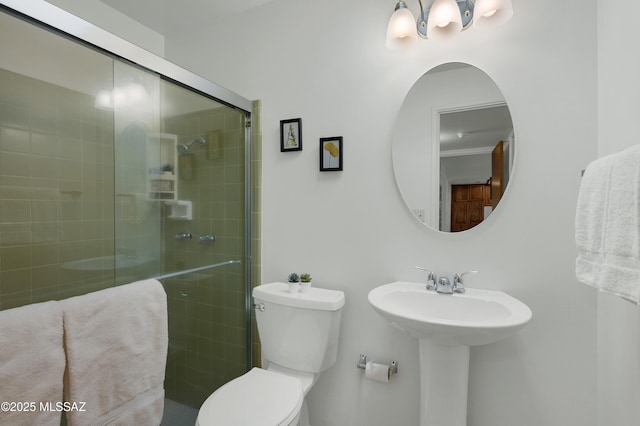 bathroom with a sink, a shower stall, and toilet