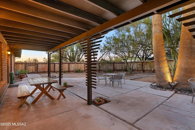 patio terrace at dusk with a fenced backyard and outdoor dining space