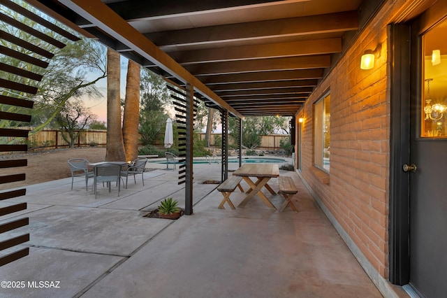 patio terrace at dusk featuring a fenced in pool, outdoor dining space, and a fenced backyard