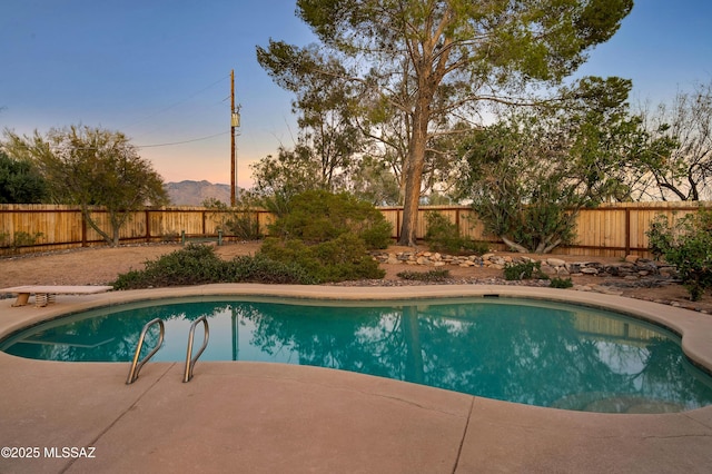 pool at dusk featuring a patio area, a fenced backyard, and a fenced in pool