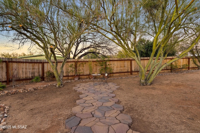 yard at dusk featuring a fenced backyard