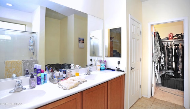 full bathroom featuring a stall shower, a walk in closet, tile patterned flooring, and a sink