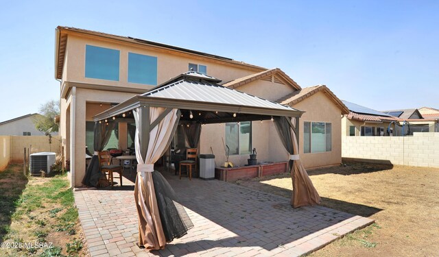 back of house featuring cooling unit, a fenced backyard, a gazebo, stucco siding, and a patio area