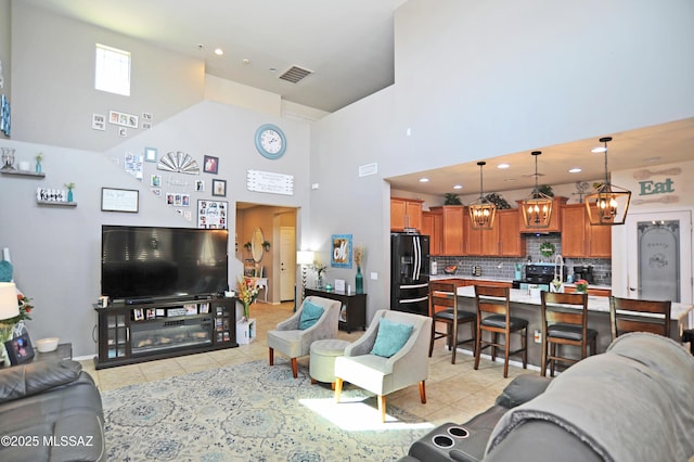 living room featuring light tile patterned floors, a high ceiling, visible vents, and recessed lighting