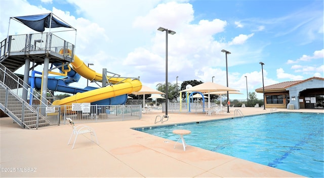 pool with a patio, stairway, fence, a water slide, and a water play area