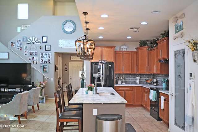 kitchen featuring a breakfast bar area, visible vents, black appliances, and light tile patterned flooring