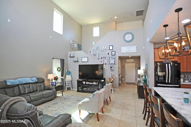 living area featuring light tile patterned floors, visible vents, and a notable chandelier