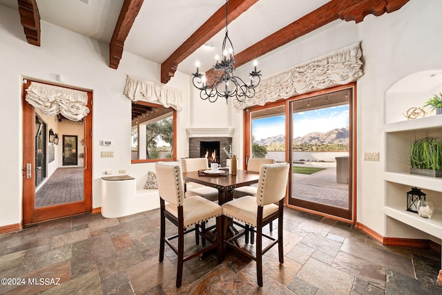 dining room with baseboards, a mountain view, stone tile flooring, and a chandelier