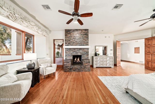 living room with a ceiling fan, visible vents, a fireplace, and wood finished floors