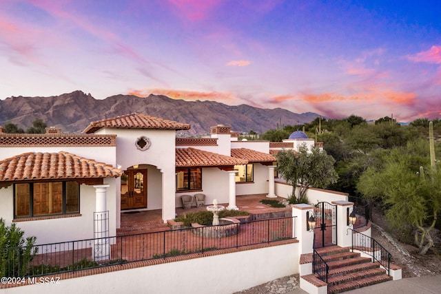 mediterranean / spanish-style home with a fenced front yard, a gate, a mountain view, and stucco siding