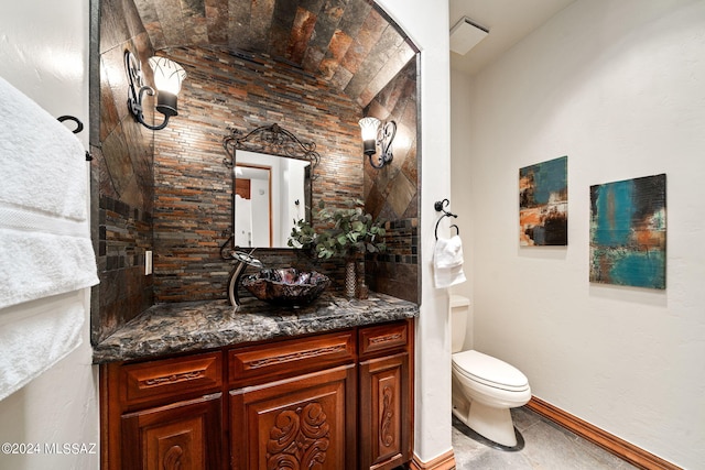 bathroom featuring toilet, baseboards, and vanity