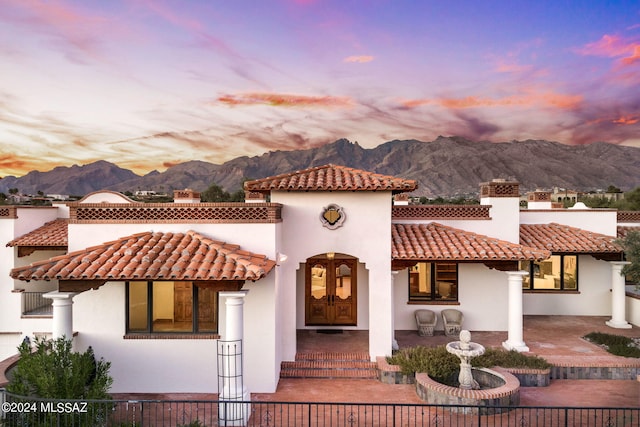 view of front of house featuring a tiled roof, a chimney, a mountain view, and stucco siding