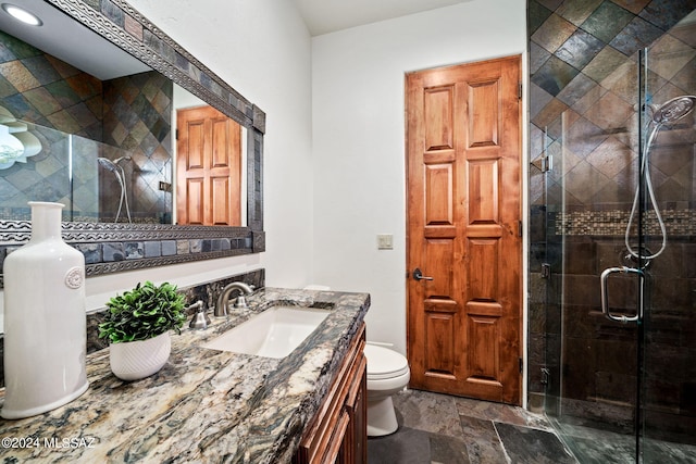 full bath featuring toilet, a shower stall, stone finish flooring, and vanity