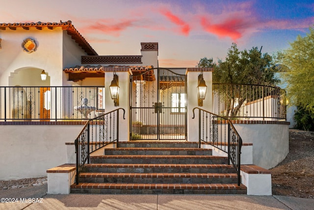 exterior space featuring a fenced front yard, a gate, a tiled roof, and stucco siding