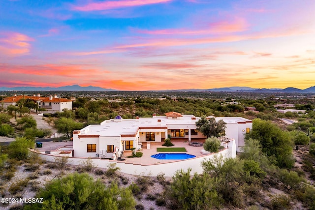 back of property at dusk with a patio area, a mountain view, and stucco siding