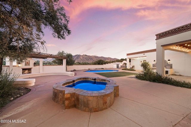 view of swimming pool with a fenced in pool, a patio, a mountain view, an in ground hot tub, and a warm lit fireplace