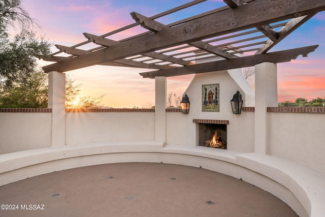 patio terrace at dusk with an outdoor brick fireplace and a pergola