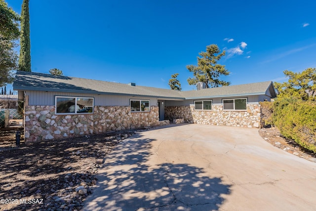 ranch-style house featuring stone siding