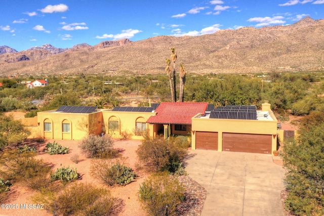 10931 E Via Tranquilla, Tucson, AZ 85749 - view of front of house with a mountain view, concrete driveway, roof mounted solar panels, and stucco siding