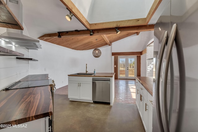 kitchen with vaulted ceiling with beams, butcher block counters, white cabinetry, french doors, and appliances with stainless steel finishes