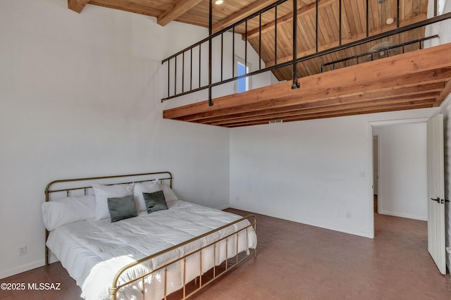 bedroom with brick floor, a high ceiling, wood ceiling, baseboards, and beam ceiling