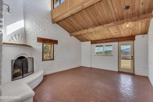 unfurnished living room with a fireplace with raised hearth, wooden ceiling, brick wall, beamed ceiling, and brick floor