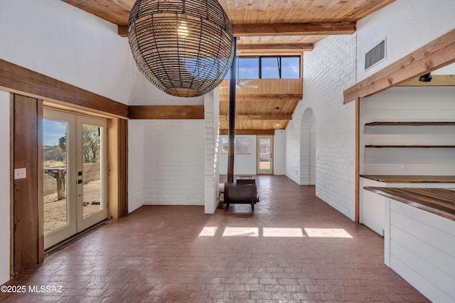 interior space with brick floor, french doors, visible vents, brick wall, and wooden ceiling