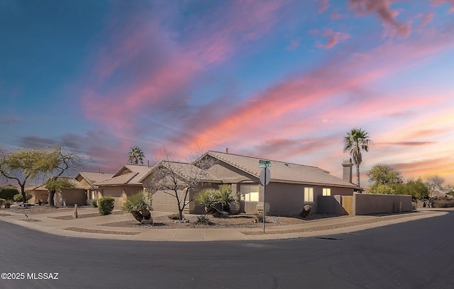 view of front facade with concrete driveway, an attached garage, and stucco siding