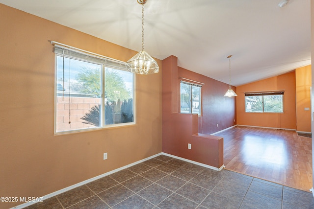 unfurnished dining area featuring vaulted ceiling, dark tile patterned flooring, and baseboards