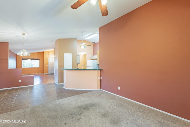 unfurnished living room with carpet floors, vaulted ceiling, ceiling fan, baseboards, and tile patterned floors