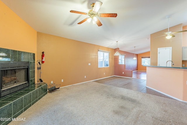 carpeted living room with a tile fireplace, lofted ceiling, ceiling fan, tile patterned floors, and a sink