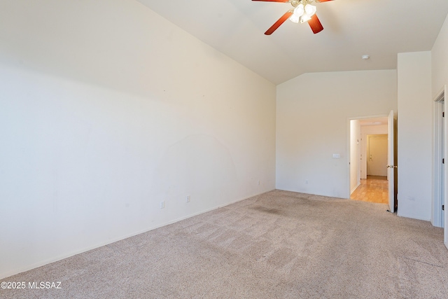 spare room featuring light carpet, vaulted ceiling, and a ceiling fan