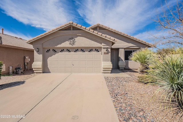 view of front of home featuring a garage, concrete driveway, a tiled roof, and stucco siding