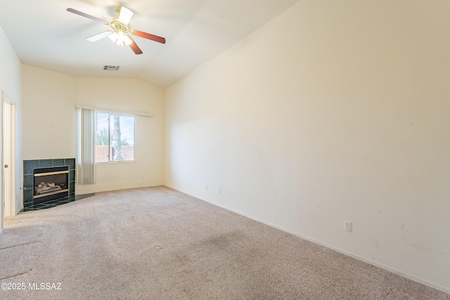 unfurnished living room with carpet floors, visible vents, a ceiling fan, vaulted ceiling, and a tiled fireplace