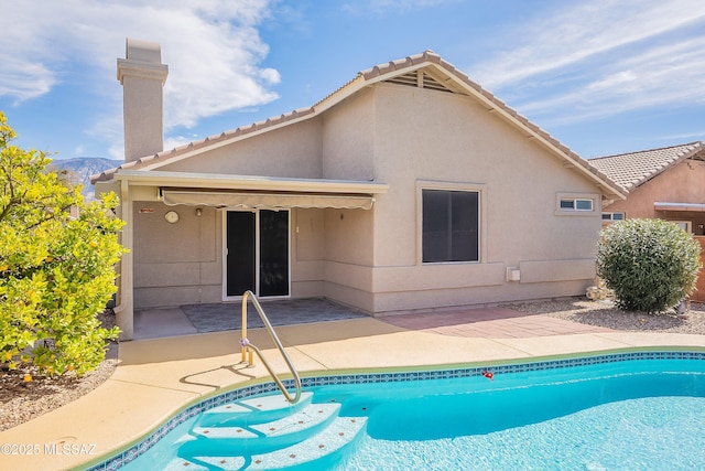 rear view of property with stucco siding, an outdoor pool, and a patio