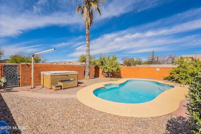 view of swimming pool with a fenced backyard, a fenced in pool, and a hot tub