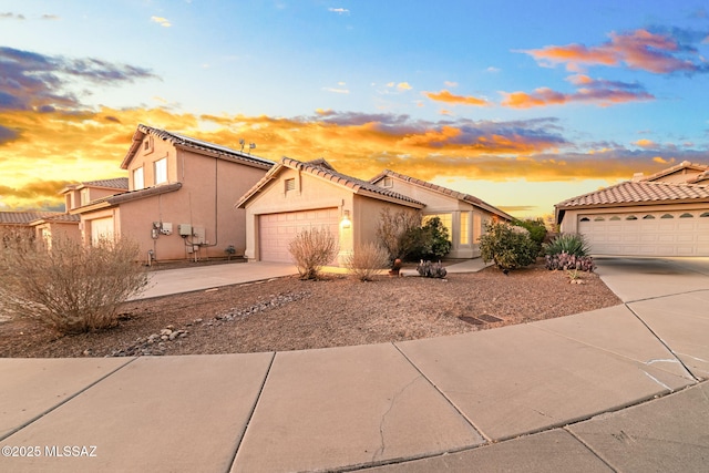 mediterranean / spanish house featuring driveway, a tile roof, a garage, and stucco siding