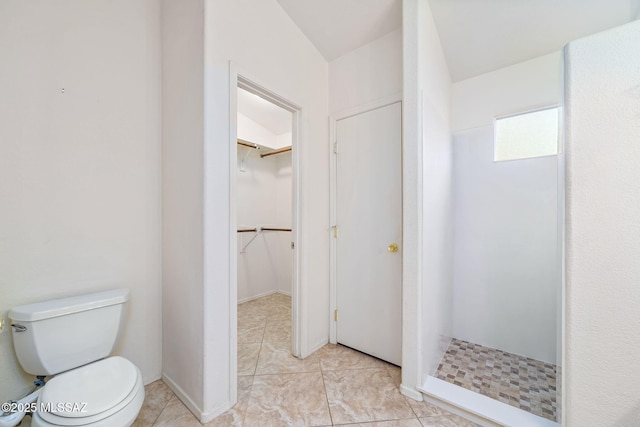 full bath featuring toilet, a stall shower, a walk in closet, and tile patterned floors